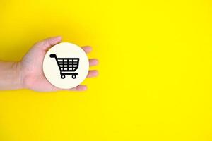 Top view hand hold of a shopping cart on a yellow background photo