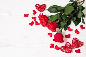 Red roses and hearts on a white wooden background. photo