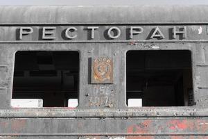 primer plano del vagón de tren destruido y oxidado con símbolos soviéticos y la inscripción -restaurante foto
