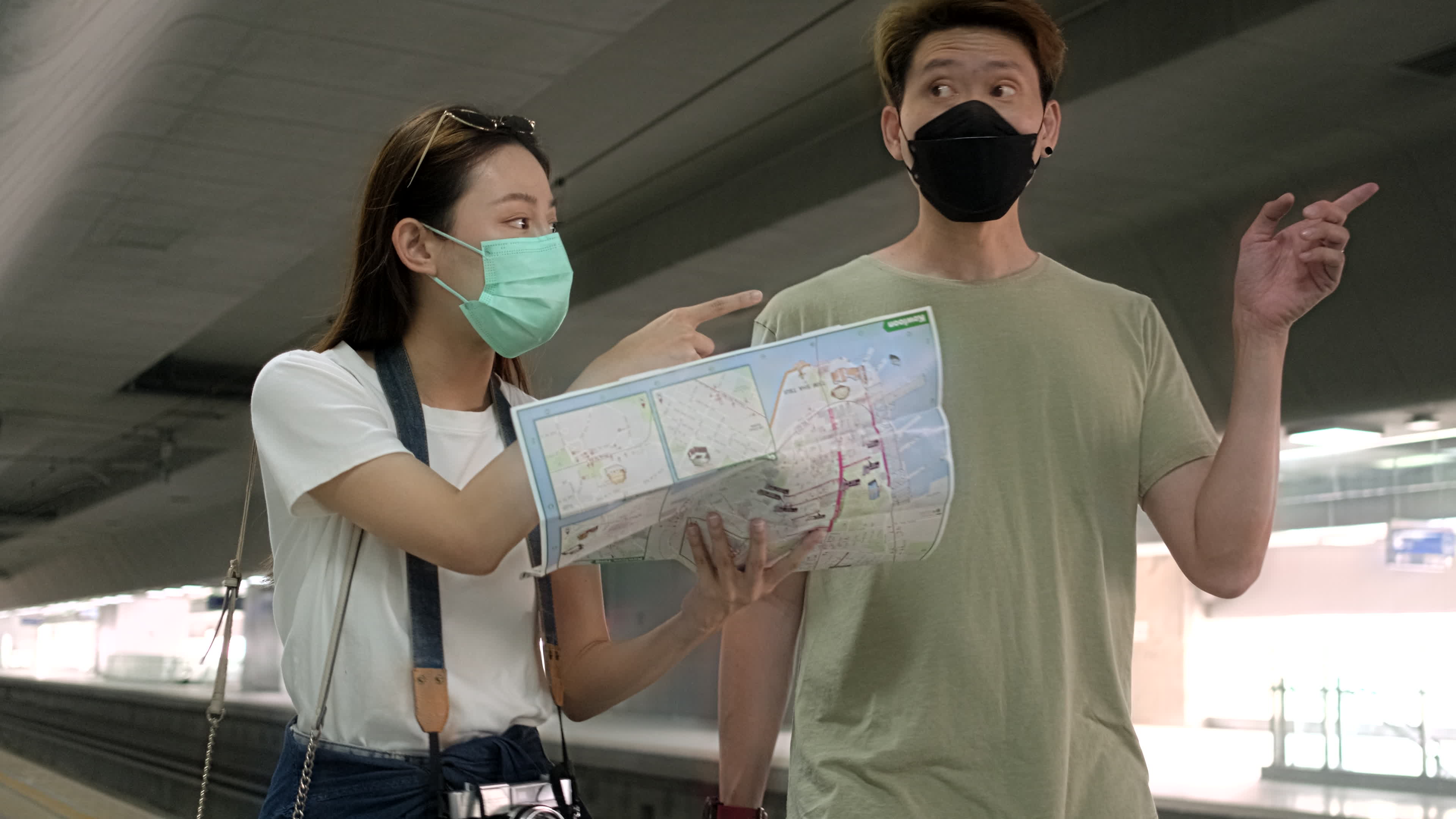 Young couple Asian tourists with face masks search information, find locations for travel at train station platform in Thailand, passenger trip lifestyle, casual transportation in journey vacation.