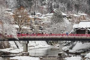 TAKAYAMA , JAPAN - January 29, 2019  Nakabashi Bridge with snow fall and Miyakawa river and tourist in winter season . Landmark of Hida - Gifu - Takayama , Japan . Landscape view photo