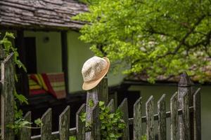 A yellow straw lady hat resting on a fence post with farmland in the background. photo