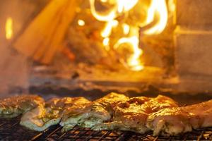 Beef steak on the grill grate, flames on background. photo