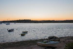 hermosa puesta de sol en el puerto de alvor. barcos, aguas tranquilas y cielo anaranjado. portimão, algarve, portugal foto