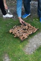 hombres irreconocibles preparando chuletas de cordero. muchas chuletas en una rejilla para cocinar a la parrilla listas para comer foto