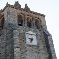 torre de piedra con tres campanas y un hermoso reloj antiguo. évora, portugal foto