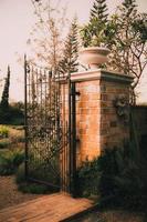 old garden cast iron steel gate on Stone column  arch entrance wall
