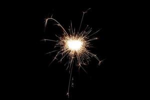 Burning sparkler isolated on black background. Fireworks theme. Light effect and texture. photo