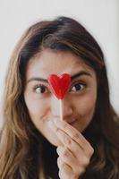 Latin woman in love with a lollipop in her hand in the shape of a heart. Valentine's Day photo