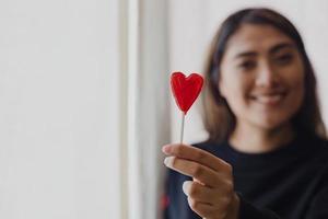 mujer latina enamorada de una piruleta en la mano en forma de corazón. día de San Valentín foto