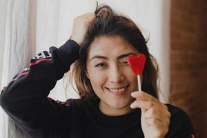 mujer latina enamorada de una piruleta en la mano en forma de corazón. día de San Valentín foto