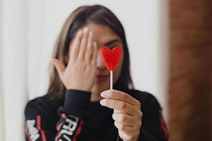 mujer latina enamorada de una piruleta en la mano en forma de corazón. día de San Valentín foto
