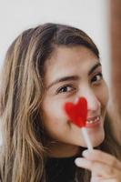 mujer latina enamorada de una piruleta en la mano en forma de corazón. día de San Valentín foto