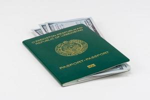 pasaporte de uzbekistán con dólares americanos sobre fondo blanco, aislado foto