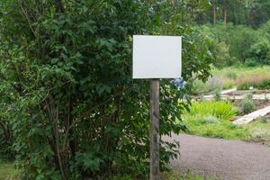 cartel en blanco en el parque sobre un fondo de árboles foto