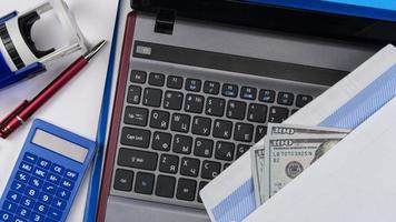 Envelope with with US dollars on laptop keyboard. Online registration. Concept - briber and corruption. Top view photo
