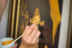 painter decorator draws Chinese pattern of leaves and man, macro shooting photo