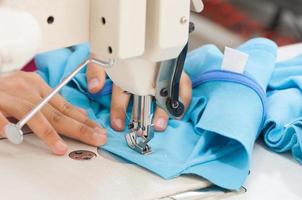 seamstress on the machine sews clothes at a garment factory photo