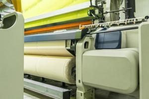 weaving loom at a textile factory, closeup. industrial fabric production line photo