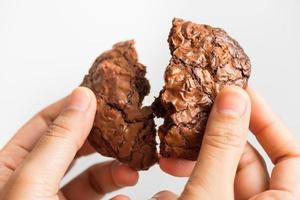 Close up hand holding sweet cookies chocolate brownie on white background, selective focus photo