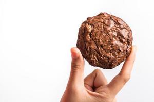 Close up hand holding sweet cookies chocolate brownie on white background, selective focus photo