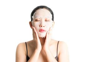 Young woman doing facial mask sheet with purifying mask on her face on white background photo