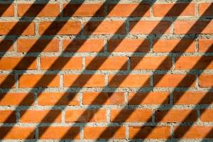 Patterned brick wall brown and has long shadows on the wall. photo