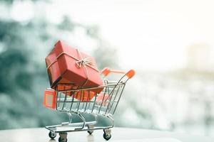 caja de regalo en carrito pequeño sobre el concepto de compras en línea. foto