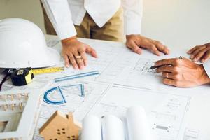 Architects working with blueprints and discussing project together at the meeting in the office. photo
