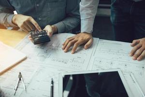 dos ingenieros trabajando juntos y usando una tableta digital buscando planos y análisis con un plan arquitectónico en el escritorio. foto