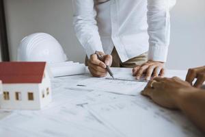 arquitecto trabajando en planos discutiendo un nuevo proyecto con un colega en la oficina. foto