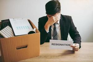 Male employee used his hand to hold the head feeling sad at his desk when he received the contract envelope for resigning from the company. photo