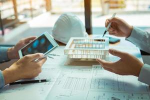 Two engineering working together and using digital tablet looking blueprint and analysis with architectural plan on desk. photo
