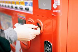 Close up of woman hand inserting coin in vending machine. photo