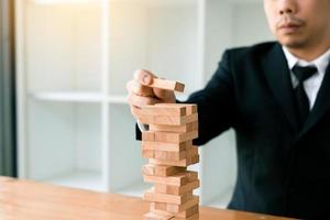 mano del hombre de negocios jugando al juego de pilas de bloques de madera con la estrategia de planificación de la gestión de proyectos. foto