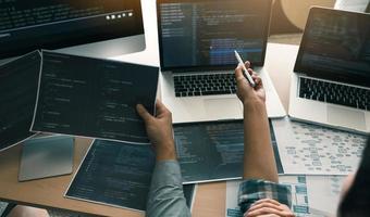 Two software developers are using computers to work together with their partner at the office desk. photo