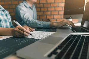Two software developers are using computers to work together with their partner at the office desk. photo