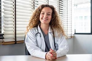 Happy smiling Caucasian woman doctor looking at the camera while having online meeting with patient, home medical consulation video call service concepts photo