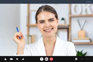 Cheerful smiling Caucasian business woman in formal suit looking at camera while making video call, work from home and online interview concepts photo