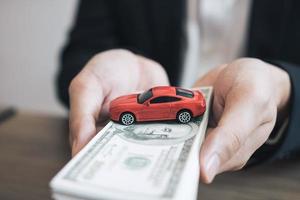 Car salespeople are submitting cash with model cars to customers with concept of buying a new car. photo