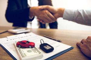 New car buyers and car salesmen are shaking hands to make agreements about car sales. photo