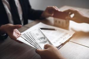 los corredores de ventas de casas y los inversionistas de bienes raíces están intercambiando con los inversionistas que están presentando efectivo en la mano del agente. foto