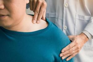 Physical therapists are using their hands to press the clavicle of the patient. photo