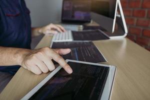 Software developer is pointing to the paper working and analyzing together the code written into the program on the computer. photo