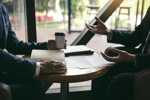 Two business partnership coworkers analysis cost work progress and gesturing with discussing a financial planning graph and company financial during a budget meeting in office room. photo