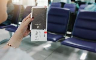 Woman hand holding passport and flight ticket in airport. photo