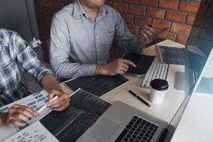 Two software developers are using computers to work together with their partner at the office desk. photo