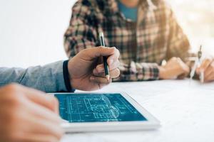 Male architect using digital tablet with architectural plan on table photo