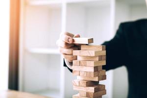 Hand of businessman playing wood blocks stacks game with planning strategy of project management. photo