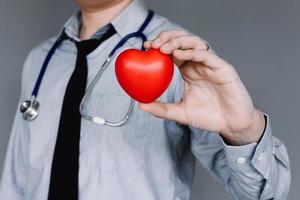 Confident doctor with casual wear and hand holding heart. photo